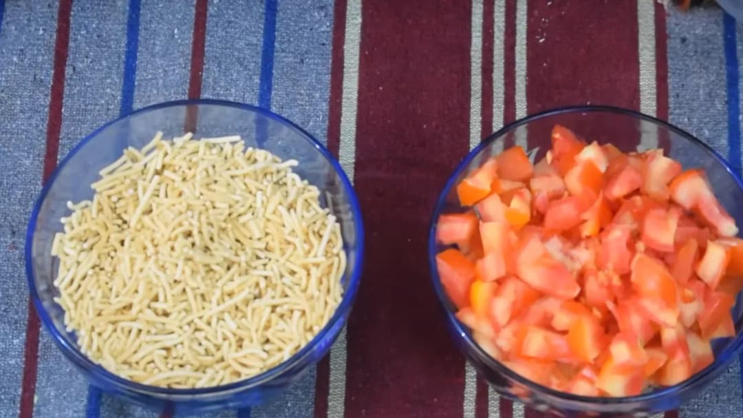 Do katoriyon me Sev Tamatar ki Sabji ki samagri — ek me namkeen sev, doosri me barik kate pake tamatar